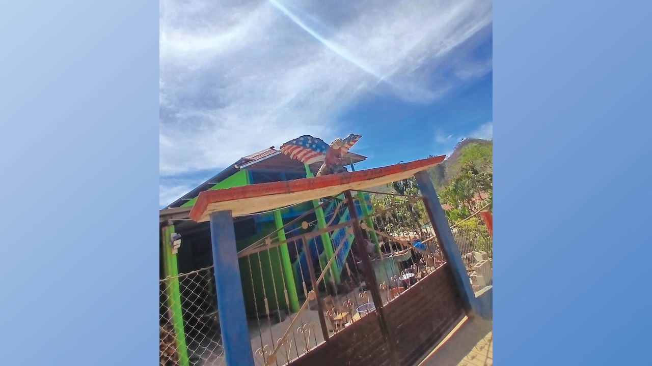A photo of a colorful house in Guatemala with a carved bald eagle painted in stars and stripes mounted over the front gate