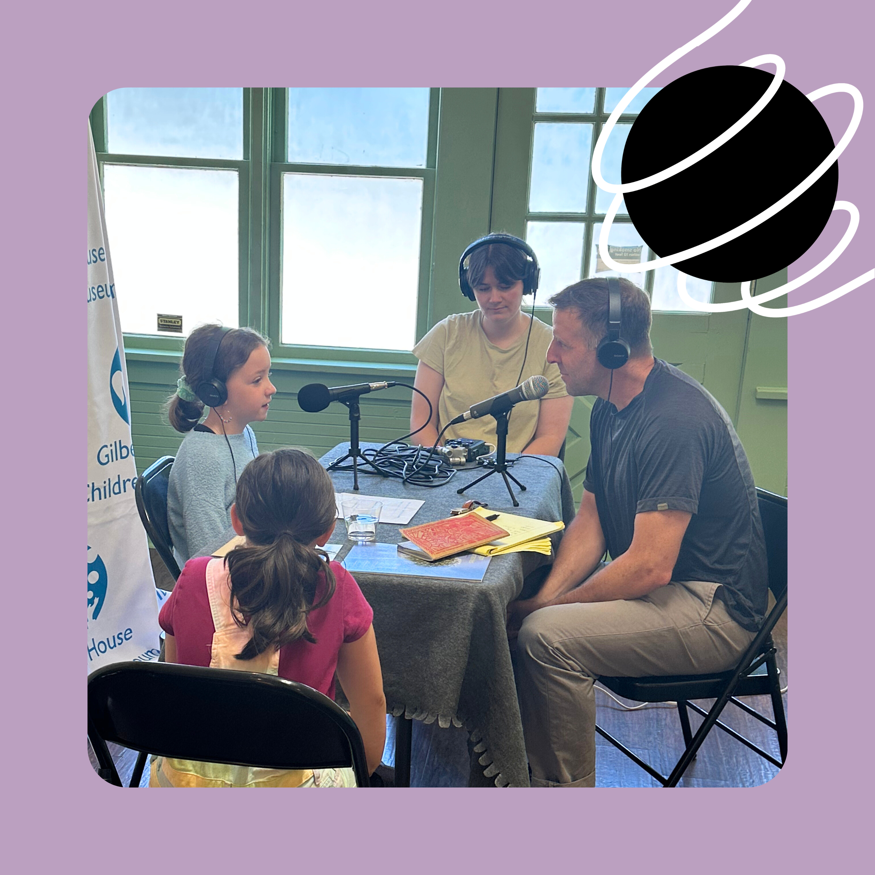 A photo of host Adam Davis, producer Anna McClain, and two children seated at a table recording a conversation at the Gilbert House Children's Museum.
