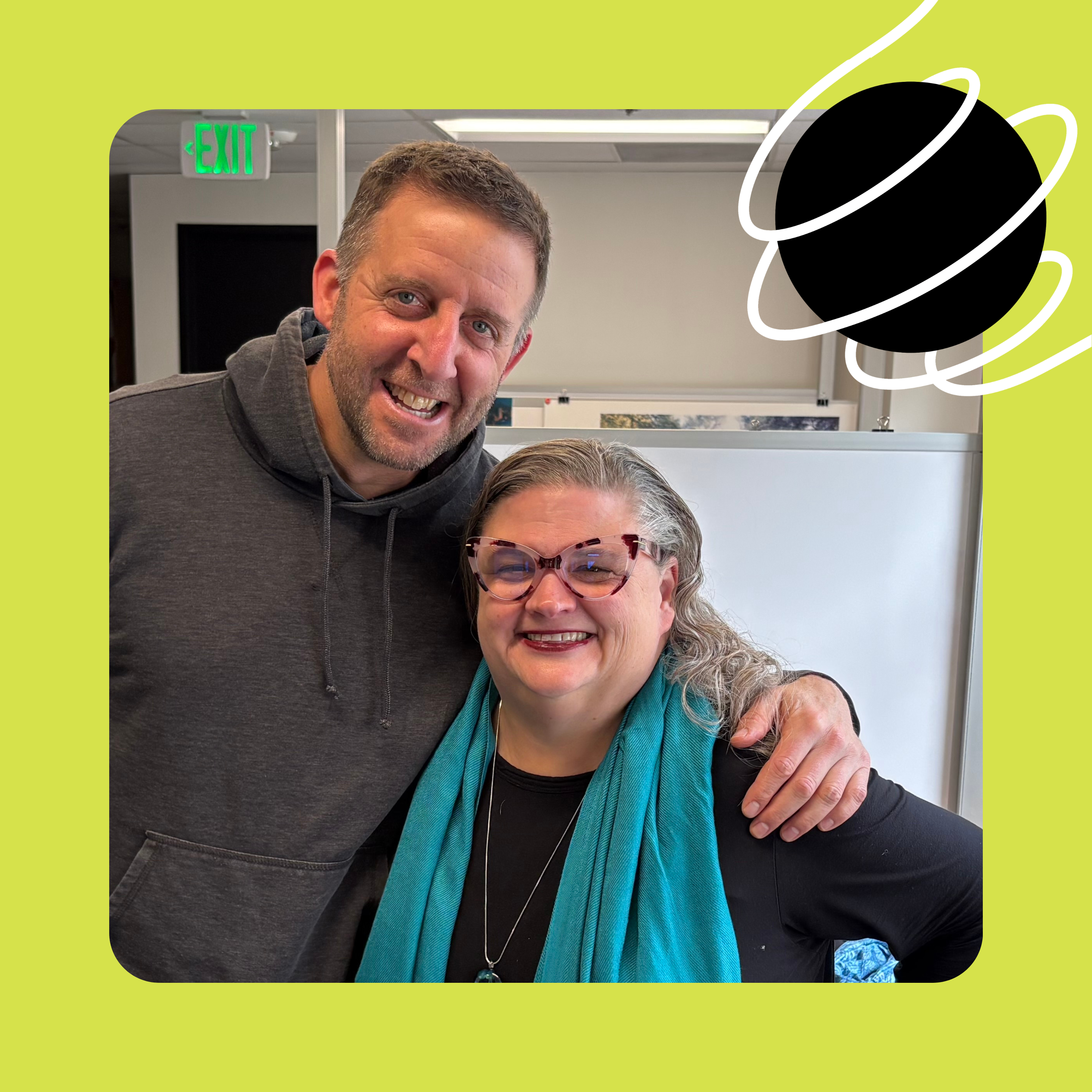 A photo of Adam Davis and CM Hall standing arm-in-arm in the Oregon Humanities office, smiling at the camera.